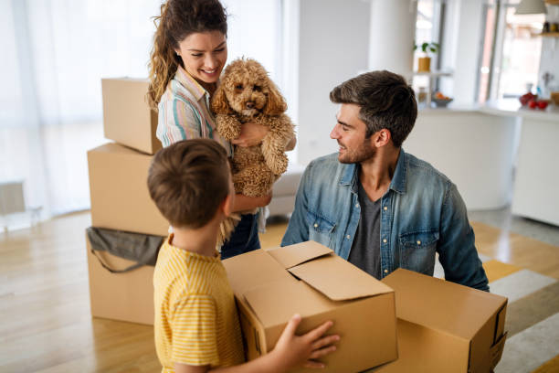 Husband and wife and their son with pet moving in new home. Husband and wife and their son with dog moving in new home. Family, relocation, moving in concept. unpacking photos stock pictures, royalty-free photos & images