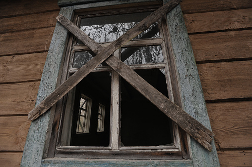 Old window of abandoned house in Chernobyl, village Denisovychi, post apocalyptic landscape, autumn season in exclusion zone, Ukraine