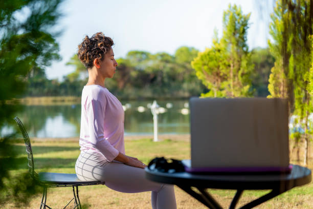 yoga trainer demonstrating yoga poses to students via video conference. entrenador de yoga que tiene clase en línea durante el coronavirus pandémico. entrenador de fitness que enseña yoga en línea a un grupo de personas cerca del lado del mar en el jardín del hotel. trabajando fuera, empleadores sin ataduras, concepto de