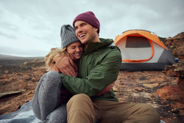 istock Happy young man hugging his smiling girlfriend and looking away during camping 1289149862