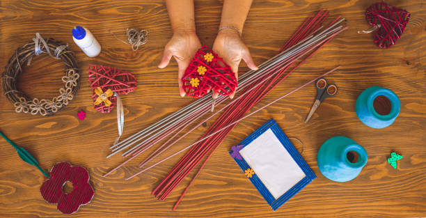 Woman hands holding red paper heart and creating paper art top view