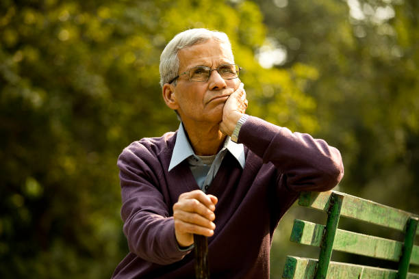 istock Thoughtful senior man sitting at park 1289150496