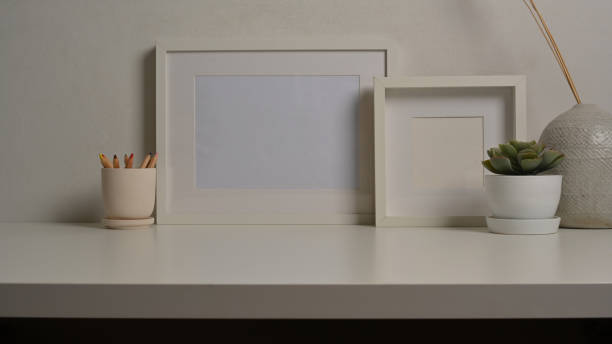 istock Home interior design with mock up frames, plant pot and vase on white desk 1289153076