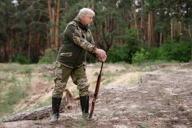 istock Hunter in Gumboots Standing with Rifle in Forest. 1289156324
