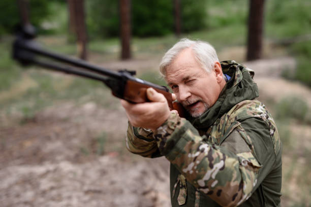 Grandfather Hunting in Summer Forest. Hunter Taking Aim with Shotgun. Old Man in Camouflage. Sports and Activities. Hunting Equipment. Senior Man Lifestyle. Woods Environment. Autumn Nature.
