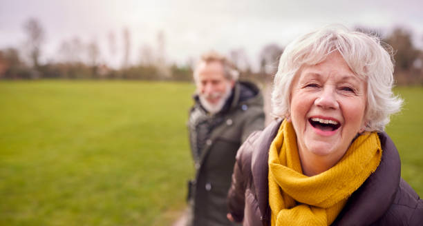 ritratto di coppia anziana amorevole che si gode la passeggiata autunnale o invernale attraverso il parco insieme - fun walk foto e immagini stock