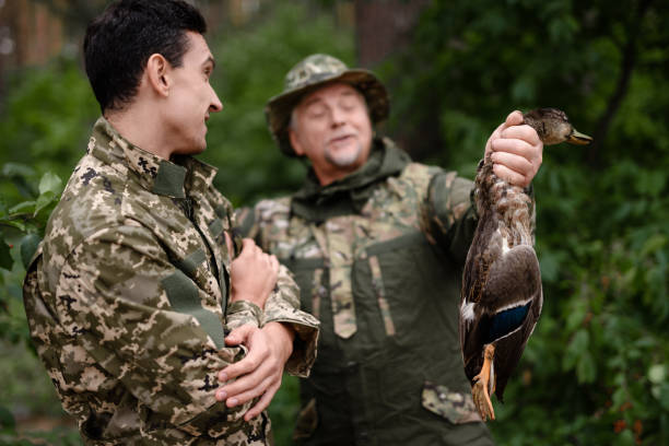 istock Wild Duck in Hunter Hands Happy Man in Camouflage. 1289157023