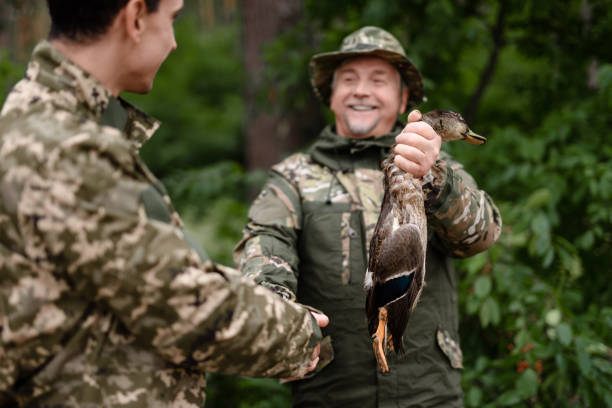 proud hunter gospodarstwa wild duck mężczyźni handshaking. - hunting two people camouflage rifle zdjęcia i obrazy z banku zdjęć