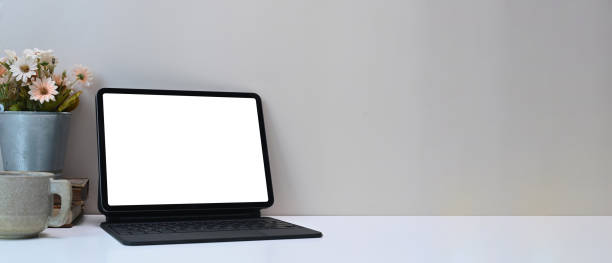 istock Minimal workspace with white blank screen monitor computer tablet, plant, coffee cup and copy space on white desk. 1289157803