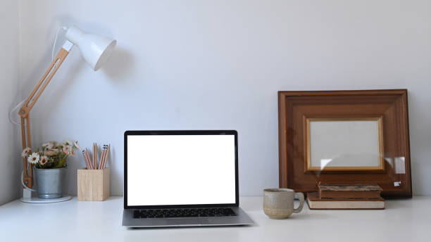 istock Creative designer workspace with white blank screen computer laptop and equipment on white desk. 1289157810