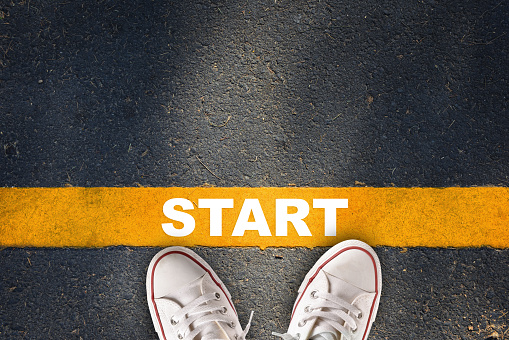 Start written on yellow line on asphalt road with sport shoe