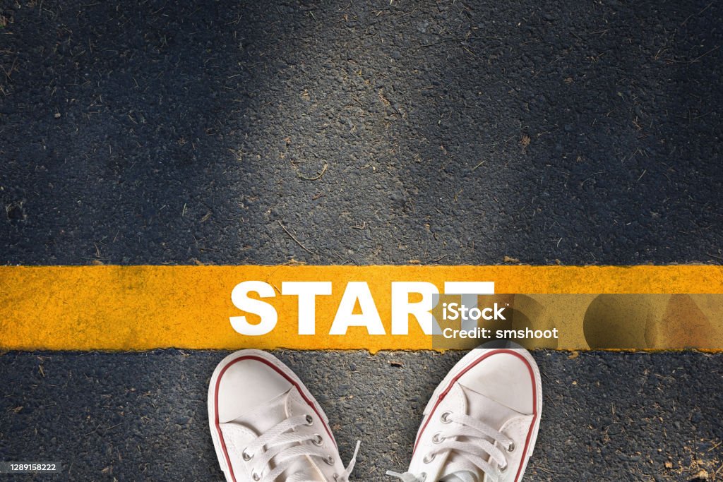 Start written on yellow line on asphalt road with sport shoe Business development challenge concept and beginning success idea Beginnings Stock Photo
