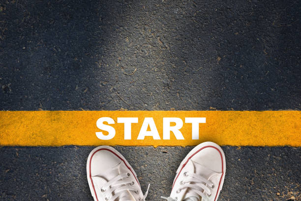 Start written on yellow line on asphalt road with sport shoe stock photo
