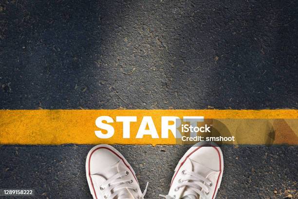 Start Written On Yellow Line On Asphalt Road With Sport Shoe Stock Photo - Download Image Now