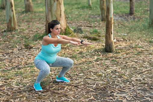 Fitness pregnant woman doing squats for strengthen pelvic floor muscles and legs. Healthy pregnancy exercise.