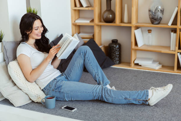 istock Cute young woman reading a book while sitting at home on a weekend 1289159189
