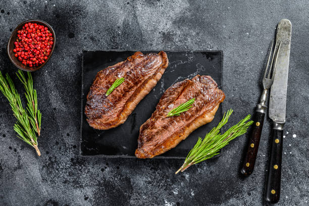 istock Grilled ramp cap steak on a stone chopping Board. Black background. Top view 1289159416