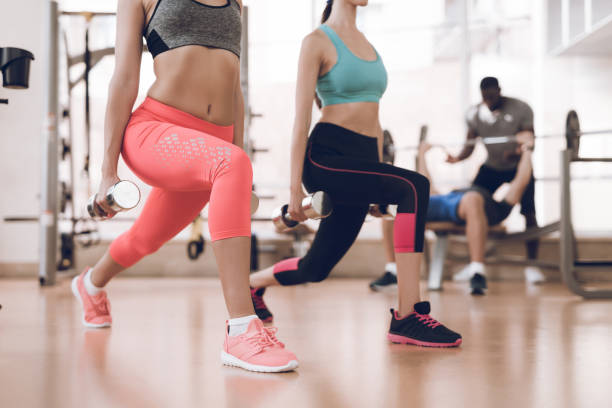 istock Girl doing exercises in a modern gym. Next to her trainer. 1289159756