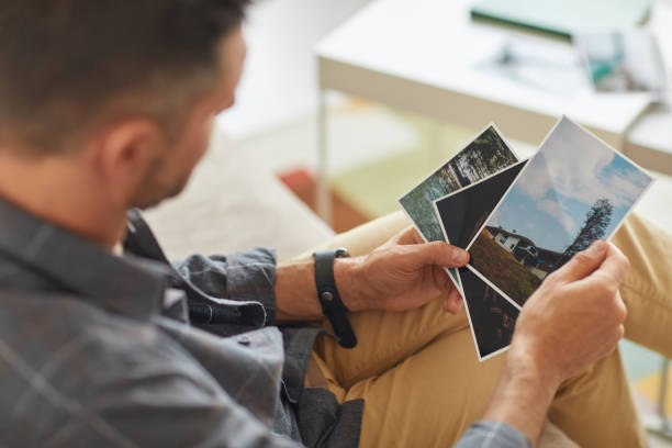 Rear view of man sitting and looking at photos with nature in his hands
