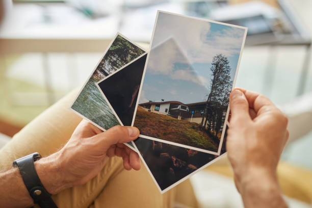 Close-up of man holding photos with beautiful landscapes in his hands