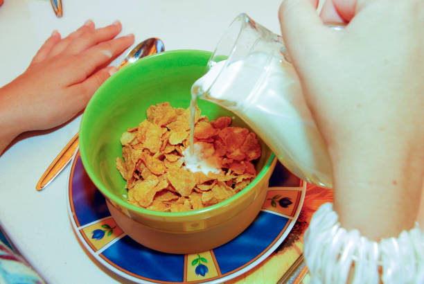 corn flakes with milk for breakfast kid is having corn flakes in a bowl with milk for breakfast guzzling stock pictures, royalty-free photos & images