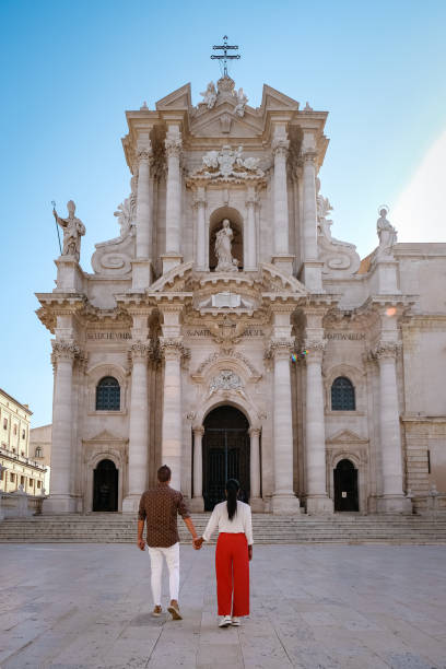 пара мужчин и женщин на citytrip ortigia в сиракузах в первой половине дня. путешествие фотография из сиракуз, италия на острове сицилия. собор плаз - citytrip стоковые фото и изображения