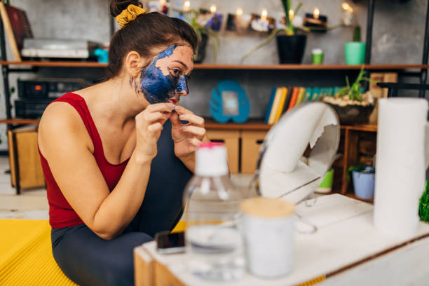 istock Healthy young woman, removing a face mask from her skin, while using a mirror to help her to evenly take off face mask 1289161023
