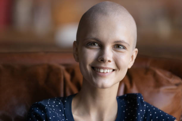 istock Optimistic female cancer patient sitting on couch looking at camera 1289162228