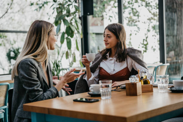istock Females drinking coffee in a tall windows cafeteria 1289162387