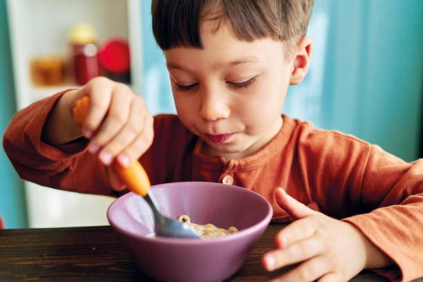 istock Cute children eating corn flakes with milk for breakfast 1289162409