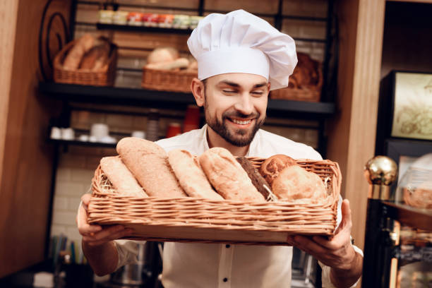 istock Young Bearded Man in White Cap Standing in Bakery. 1289162559