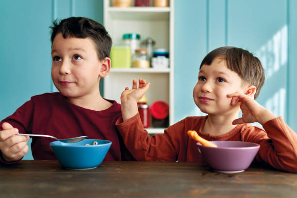 istock Cute children eating corn flakes with milk for breakfast 1289162579