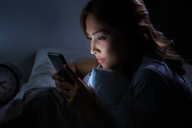 istock Young woman using a smartphone in her bed at night 1289163908