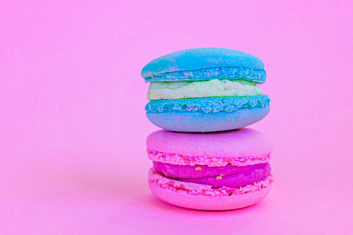 Sweet almond colorful unicorn blue pink macaron or macaroon dessert cake isolated on trendy pink pastel background. French sweet cookie. Minimal food bakery concept. Copy space