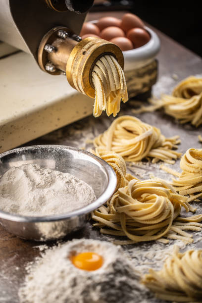 istock Flour, eggs and a pasta maker producing fresh Italian fettuccine. 1289165978