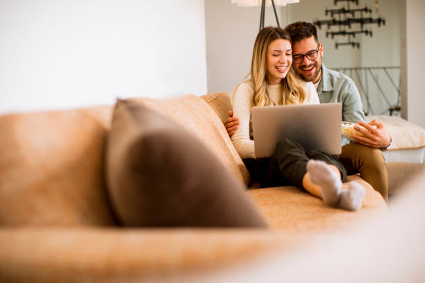 istock Young couple using laptop together while sitting on sofa at home 1289166655