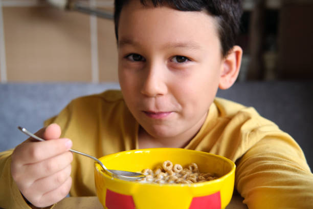 istock Cute children eating corn flakes with milk for breakfast 1289167568