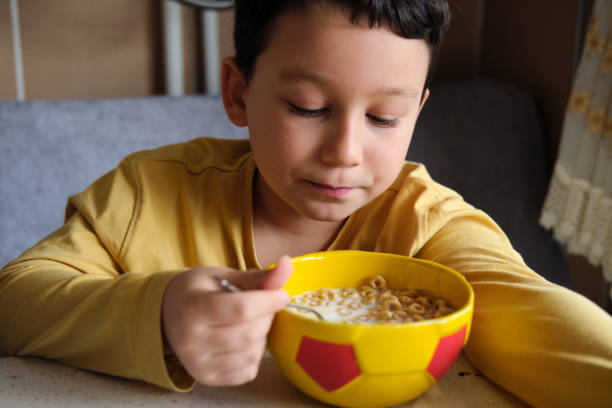 istock Cute children eating corn flakes with milk for breakfast 1289167578