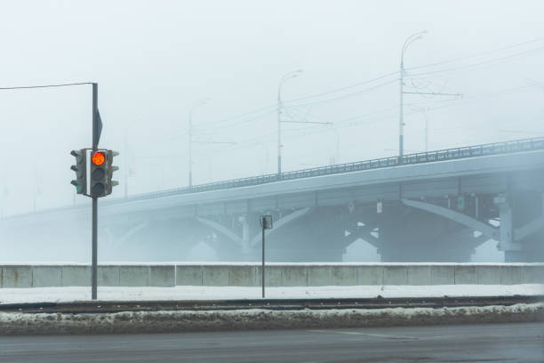 Red traffic light at the intersection in winter city. View of the intersection of the road near the Chernavsky bridge in Voronezh in winter. Empty foggy city without people. Traffic control.