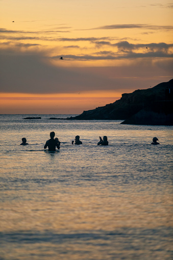 Unrecognisable group of friends open water swimming at dawn.