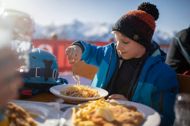 kleiner junge beim mittagessen im alpinen skirestaurant - apres ski friendship skiing enjoyment stock-fotos und bilder