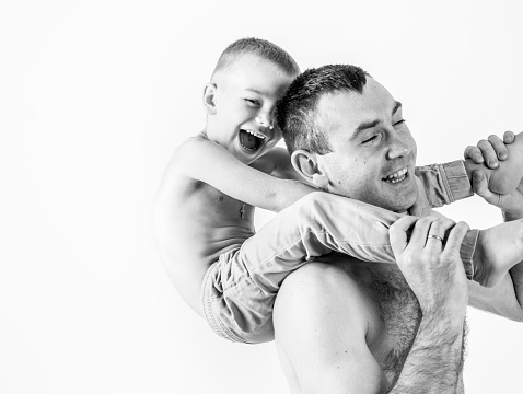 father plays with his son, lifting him on his shoulder. black and white photo
