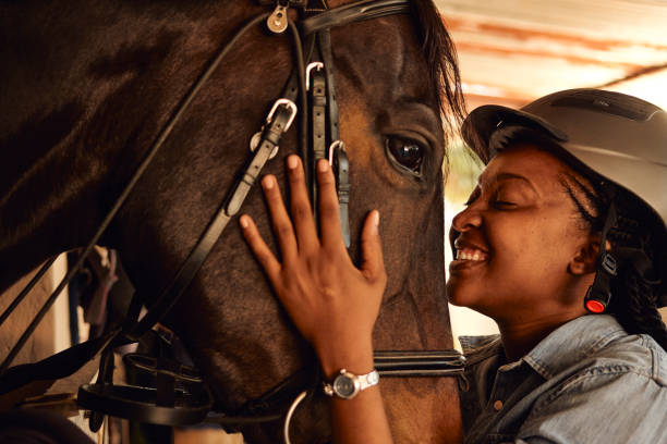 my one true love A young black African woman blissfully smiling big while holding her horse’s face embracing all horse riding stock pictures, royalty-free photos & images