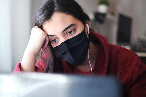 Una mujer que lleva una máscara negra tratando de mantenerse concentrada mientras trabaja desde casa debido a Covid-19, luchando con ansiedad y depresión. photo
