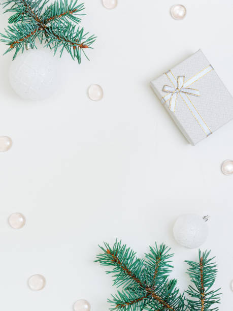 istock white festive background: branches of a christmas tree, balls, beads and a small gift box. Copy Space Center 1289175481