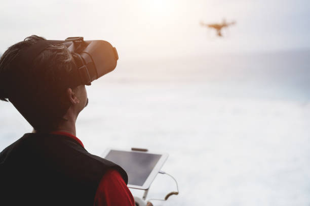 Fpv drone pilot flying with quadcopter outdoor on the beach - Technology concept - Focus on head Fpv drone pilot flying with quadcopter outdoor on the beach - Technology concept - Focus on head drone point of view stock pictures, royalty-free photos & images