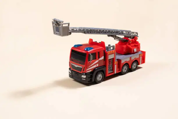 Photo of Toy typewriter on beige background red fire truck made of plastic. For the toy store, a gift for the boy