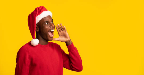 istock Black Guy In Santa Hat Shouting At Copy Space, Making Christmas Announcement 1289177119