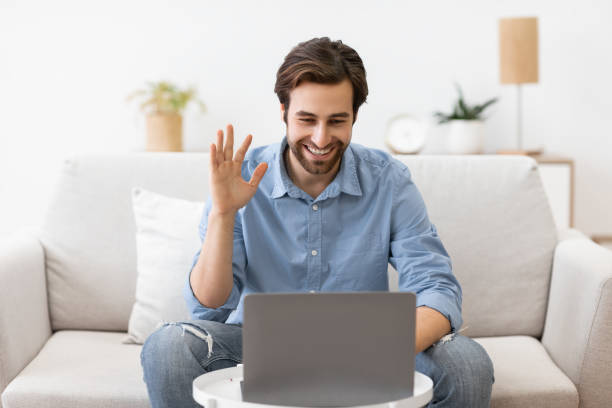 istock Man Waving To Laptop Making Video Call Sitting At Home 1289177969