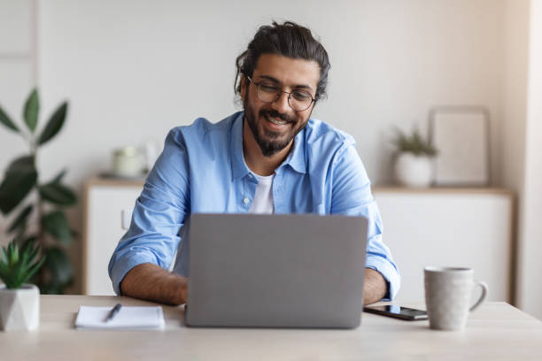 istock Freelance Work. Happy Millennial Indian Man Working On Computer At Home Office 1289179883